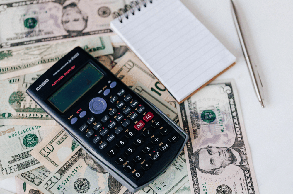 stock image of cash, calculator, pen and paper