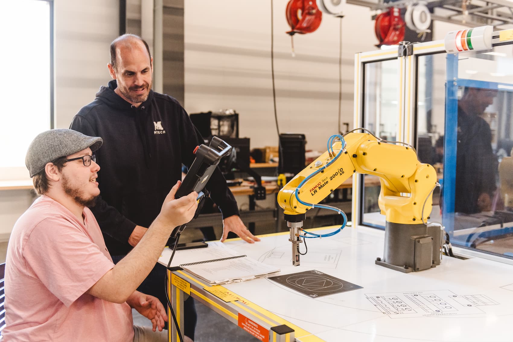 A student operating a robotic arm with an instructors help