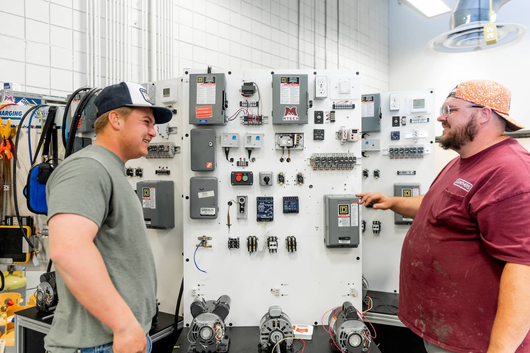 Two students standing at a wall of electrical systems