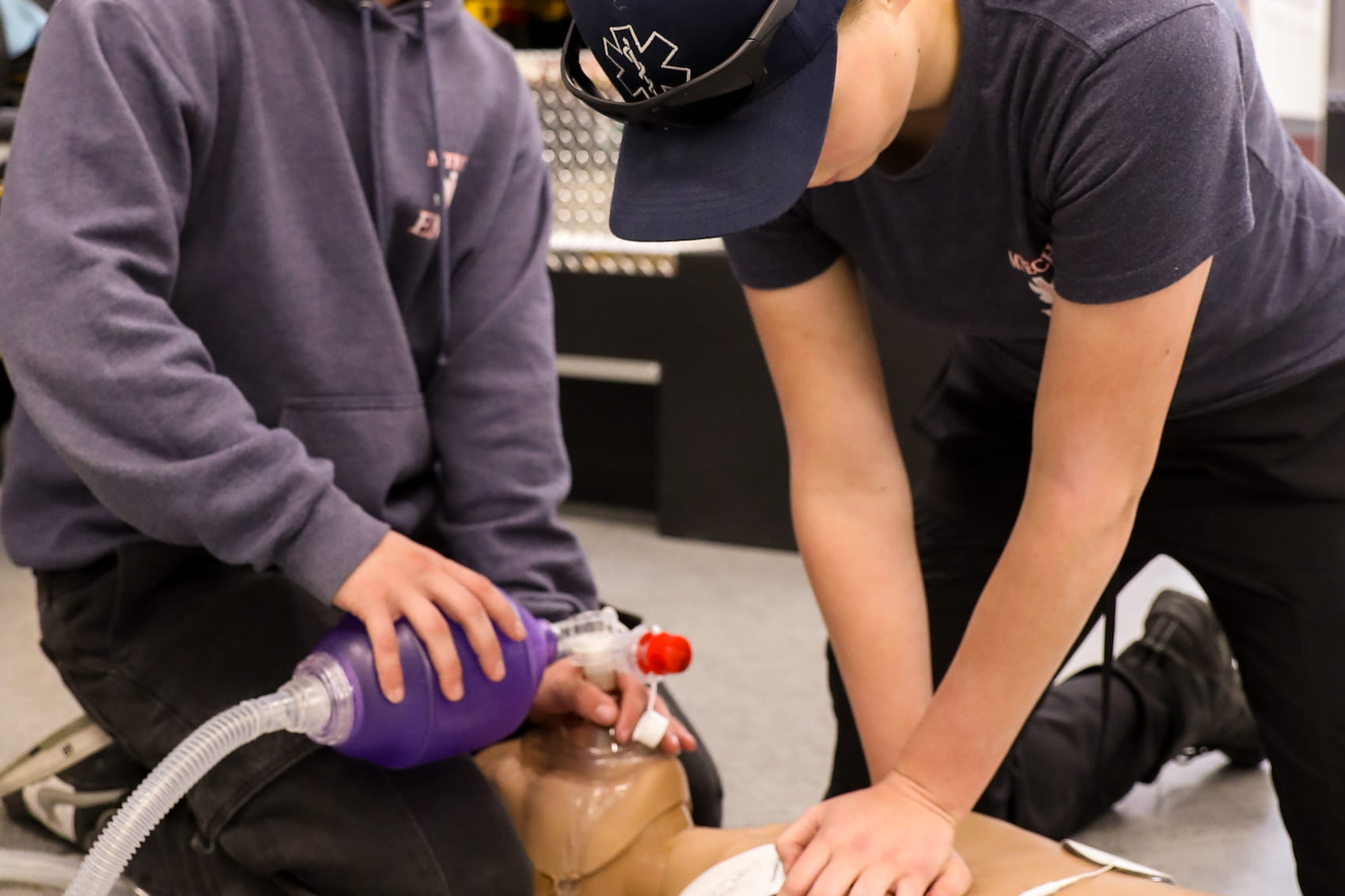 Students performing CPR and using an Ambu bag to practice resuscitating a manikin