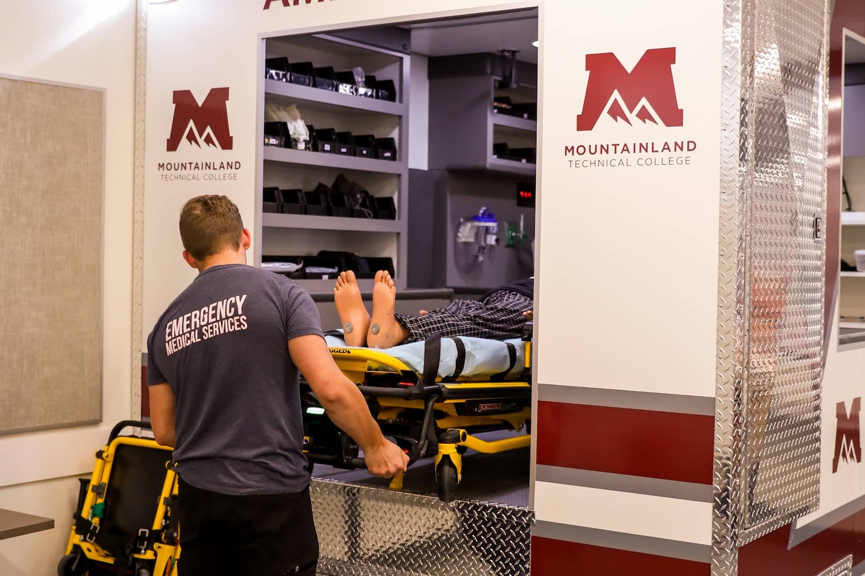 Students loading a manikin on a stretcher into an ambulance