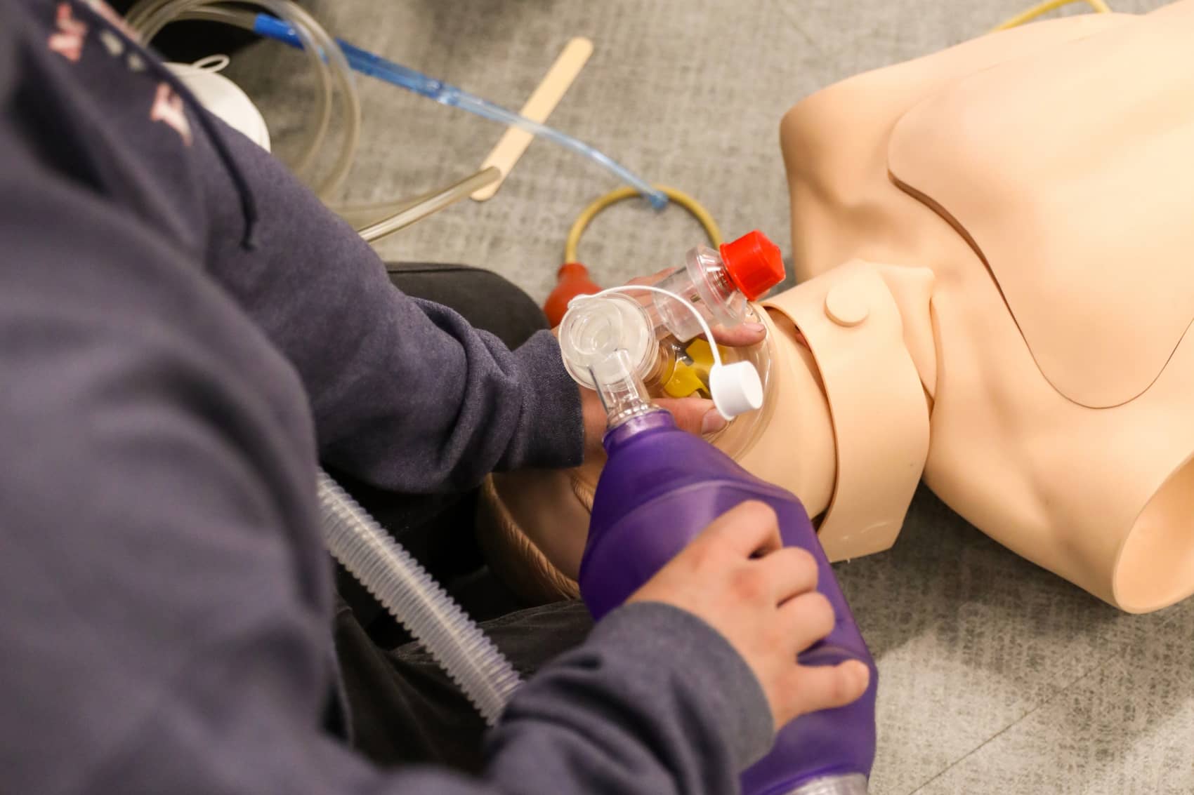 Student using an Ambu bag to practice resuscitating a manikin