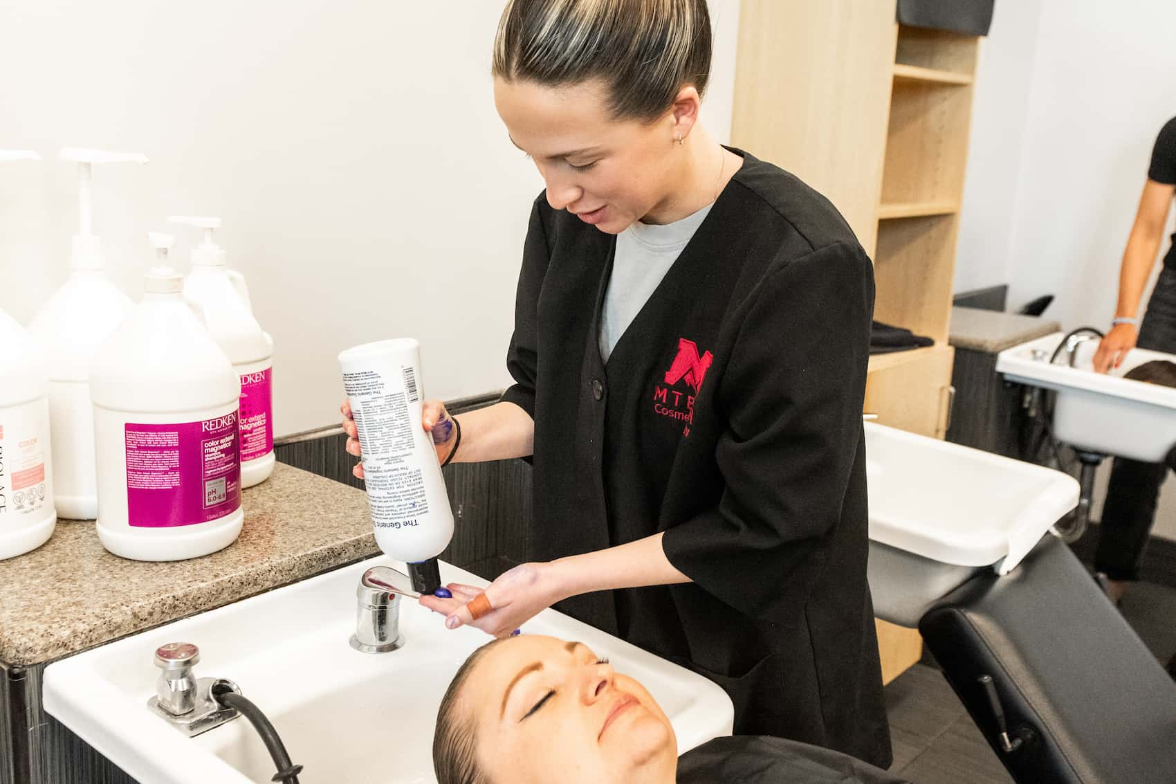 Cosmetology student shampooing another student's hair