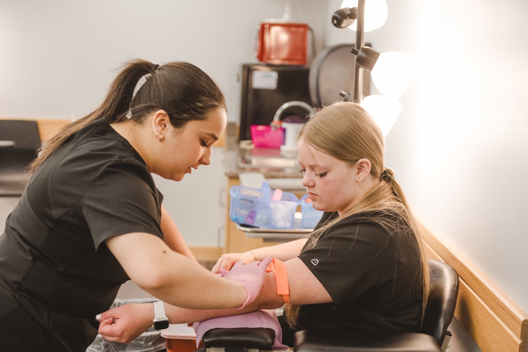 Student preparing other student's arm for IV